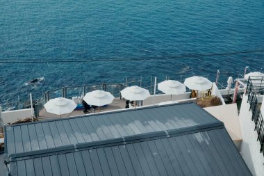 Beyaz şemsiyeli ve deniz kenarındaki masalı bir restoran terası manzarası.