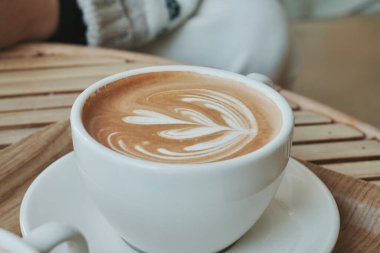 Sütlü sütlü kahve fincanını kapat. Latte sanatıyla süslenmiş.