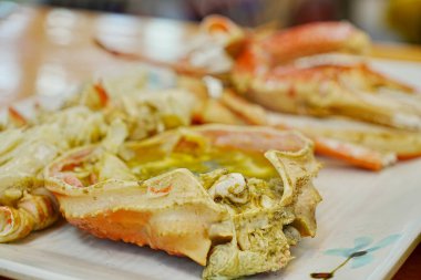 Beyaz tabakta servis edilen pişmiş yengeçler.