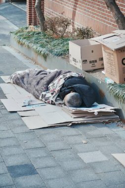 Dışarıda kartonda uyuyan biri var.