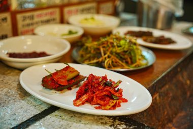 Beyaz tabaklarda servis edilen çeşitli yemekler.