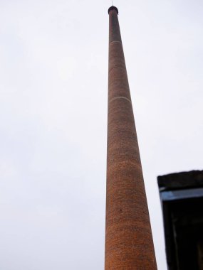 Bulutlu gökyüzüne karşı uzun tuğla baca