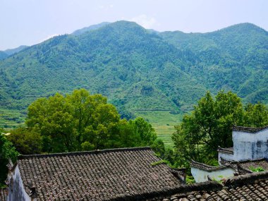 Geleneksel çatıların arkasındaki yemyeşil dağlar