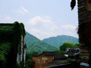 Mavi gökyüzünün altında bulutlu yeşil dağlar