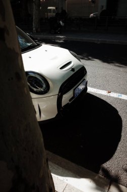 Beyaz araba ağaç gölgesinin yanına park edilmiş.