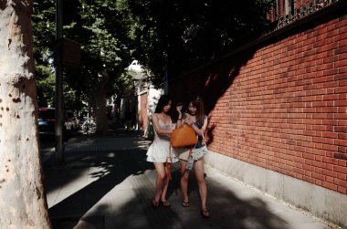 Tuğla duvar boyunca yürüyen iki kadın