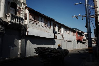 Adam boş cadde binaları boyunca el arabası sürüyor.