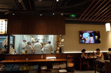 Şefler cam pencerenin arkasında yemek hazırlıyor