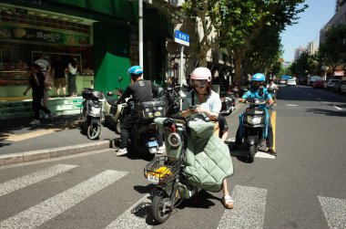 Scooter süren kişi pembe kask takıyor.