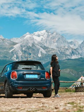 Mavi araba dağlarının yanında duran kişi