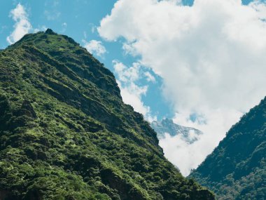 Parlak mavi gökyüzünün altında yemyeşil dağlar