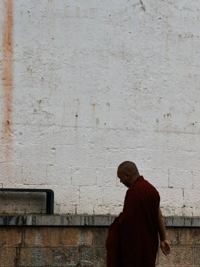 Keşiş dokulu beyaz duvarın yanında yürüyor