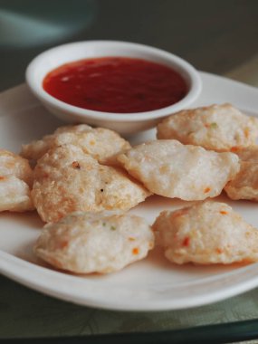 Kırmızı sos ile servis edilen çıtır atıştırmalıklar.