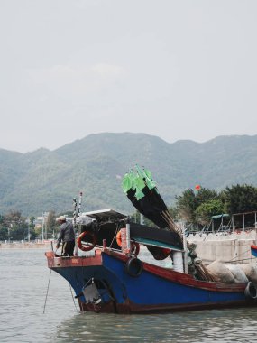 Yeşil dağların yakınında renkli bir balıkçı teknesi