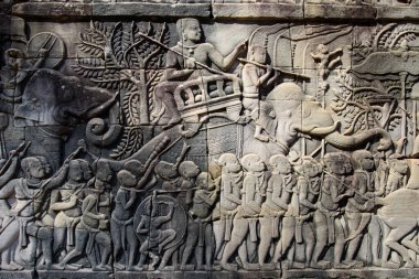 Bayon Tapınağı, Angkor, Kamboçya 'daki taştan kabartmalar, Angkor döneminin kültürel, sosyal ve sanatsal zenginliğini yansıtan Khmer halkının hem askeri faaliyetlerini hem de günlük aktivitelerini tasvir ediyor..
