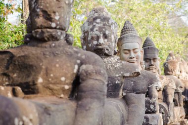 Bayon Tapınağı 'ndaki Naga taş köprüsünde, Angkor Thom, Hindu mitolojisini sembolize eden ve zarif Khmer taş oymalarını sergileyen koruyucu tanrılar ve iblisler vardır..