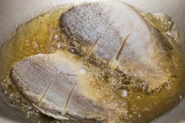 Tayland usulü yılan derisi gourami tavada kızgın yağla kızartılıyor, çıtır çıtır altın dokuları gösteriyor..