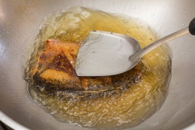 Tayland usulü yılan derisi gourami tavada kızgın yağla kızartılıyor, çıtır çıtır altın dokuları gösteriyor..