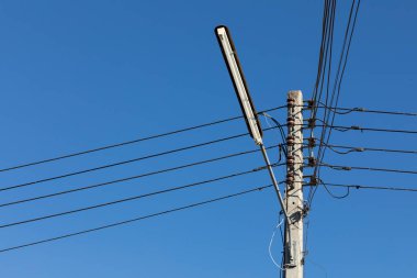 Elektrik hatları ve iletişim hatları mavi gökyüzü ile elektrik direklerinde.