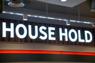 Ev Mağazası İmzası: Ahşap Arkaplanda Beyaz Harfler. Parlak ışıklandırılmış, düşük açılı bir 'Ev Bekleme' tabelası. Temiz, modern bir estetik. Ahşap kaplamalı arka planı ve tenha ışıklandırması var. Hor.