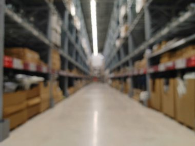 Karton kutuları ve bulanık manzaralı depo rafları. Yumuşak odak, uzun koridor perspektifi bir depoda. Parlak floresan aydınlatma, nötr renk paleti, endüstriyel estetik. Sığ d.