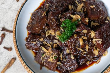 Yeşil Rimmed Bowl 'da Biftek Rendang Curry. Taze maydanoz ve kızarmış arpacık soğanlarıyla süslenmiş koyu renkli biftek rendang köri. Sıcak, davetkar aydınlatma ve sığ alan derinliği.