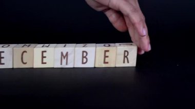 Siyah arka planda yaşayan genç bir Asyalı kadın tarafından tahtadan bloklar yerine harf sıralamasının değiştirilmesi.