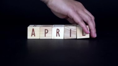 Siyah arka planda yaşayan genç bir Asyalı kadın tarafından taşınan harf dizilimini APRIL 'den MAY' e çevirme hareketi