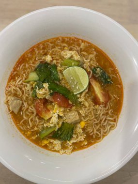 Yumurtalı, domatesli, yeşil sebzeli ve limonlu bir kase baharatlı hazır şehriye..