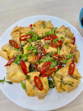 Biber soslu altın tofu pufları ve beyaz tabakta soslu kızarmış arpacık soğanı.