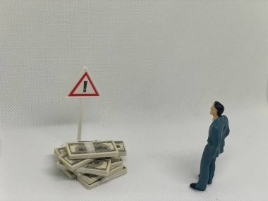 Risk değerlendirmesi ve farkındalığı temsil eden paranın üzerindeki uyarı işaretine bakan kişi