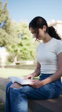 Öğrenci, Granada, İspanya 'da alçak bir duvarda oturan bir kitap okuyor.