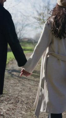 Sonbaharda parkta el ele yürüyen sevgi dolu bir çiftin yavaş çekim arkası görüntüsü