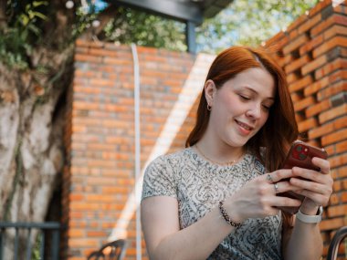 Dış merdiven ve cam mimarisi yakınında akıllı telefondan konuşan spor ceket giyen, akıllı ve akıllı giyinen, mobil iletişim ve iş görüşmesi kavramını kullanan genç bir kadının yan görüntüsü..