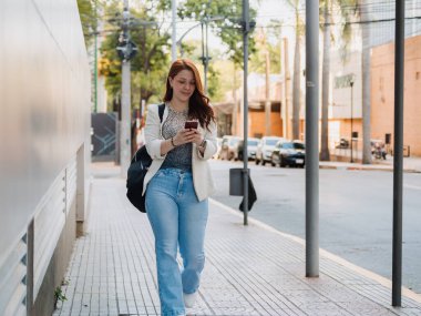 İş kadını, elinde tabletle modern bir kafe salonunda telefon görüşmesi yapıyor. Uzaktan kumandalı iş ve profesyonel iletişim kavramı..