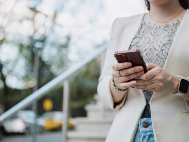 Bir kadının elleri merdivenlerin yanında akıllı telefonu tutarken, bir mesaj yazarken, iş kıyafetleri akıllı, mobil iletişim ve teknoloji kavramına sahip..