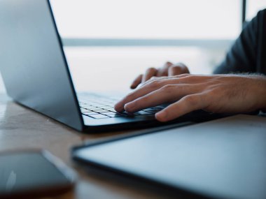 Çalışma masasında dizüstü bilgisayarda yazan eller, üretkenlik ve dijital bağlantıya odaklanmış, uzaktan çalışma ve çevrimiçi iş kavramları için ideal.