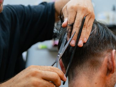 Berber dükkanında kısa saç keserken, keskin aletleri, sabit elleri ve profesyonel tımar tekniğini vurgularken çekilen makas görüntüsü..