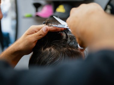 Berberin, berber dükkanında saç makasıyla saç kesmesi, çalışma sürecini göstermesi ve modern erkek bakımı ve kişisel bakım hizmetlerini rafine etmesi..