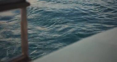 Mavi okyanus yüzeyine yakın çekim dalgalanmaları ve tekne uykusuyla, dinamik su dokusu arka planlar ve seyahat görselleri için.