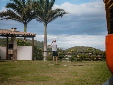 Yeşil bir açık alanda sırt üstü uzanan insan figürü tepeler, ağaçlar ve bulutlu gökyüzü olan bir manzaraya bakıyor. Seyahat, keşif, kırsal turizm, özgürlük, dinlenme ve doğa ile bağlantı kavramları için kullanışlı bir resim.