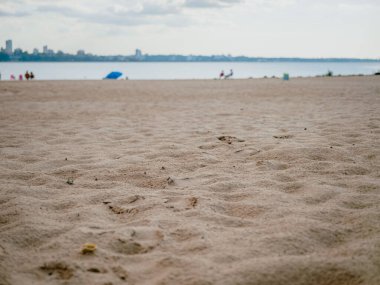 Sahilde, deniz ve ufuk arkaplanının odak noktasından yavaşça uzaklaşmış kumlara yaklaş. Arkaplan, grafik tasarımı, yaz afişleri, turizm, dinlenme, sakinlik ve tatil kavramları olarak ideal görüntü.
