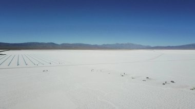 Arkasında mavi bir gökyüzü olan büyük, boş bir çöl. Gökyüzü açık ve güneş parlıyor.