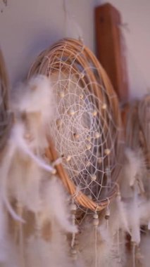 Üzerinde beyaz tüyler sallanan güzel bir düş kapanı. Tüyler bir hareket ve akış hissi yaratacak şekilde sıralanmış. Düş kapanı kahverengi malzemeden yapılmıştır.