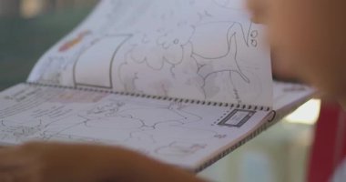 Bir insan üzerinde harita olan bir kitaba bakıyor. Kitap, içinde bir kişinin resmi olan bir sayfayı açıyor.