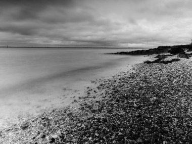 black and white beach with stones and water