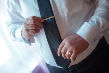 Damat, kelepçeyi evlilik yüzüğüyle ayarlıyor. Damat ellerini kapat kol düğmesini düzelt ve yemin tarzının simgesini göster ve düğün hazırlıklarını yap.