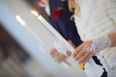 Gelin kilisede beyaz bir mum tutuyor.