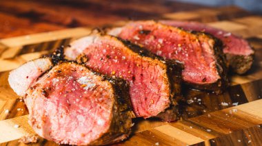 Dilimlenmiş biftek ve ahşap bir masada baharatlar..