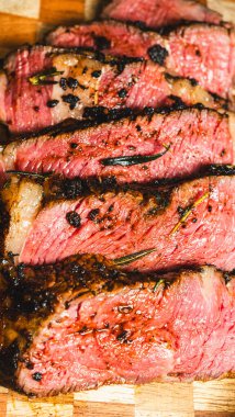 Tahta masada baharat ve otlarla dilimlenmiş taze biftek.